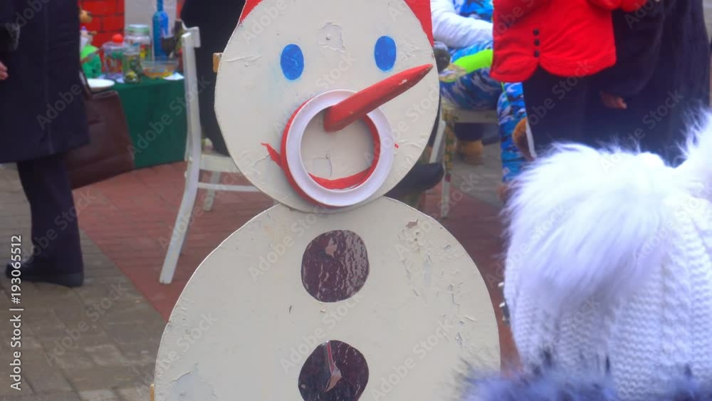 little girl throws a ring into the nose of the snowman. vídeo de Stock Adobe Stock