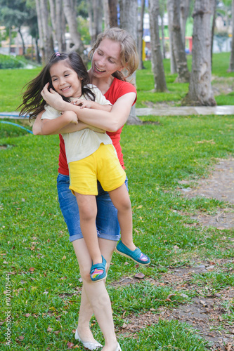 Happy biracial family in the summer park - caucasian mom with her little latin daughter having fun. 