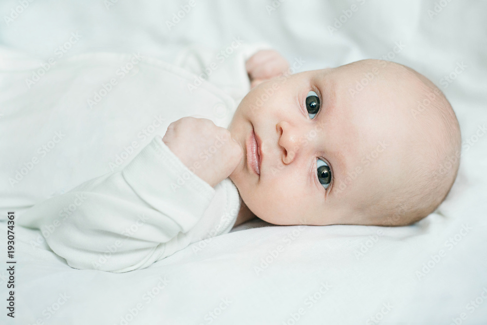 Close up portrait of three-month-old baby boy lying on white linen Close up portrait of three-month-old baby boy lying on white linen