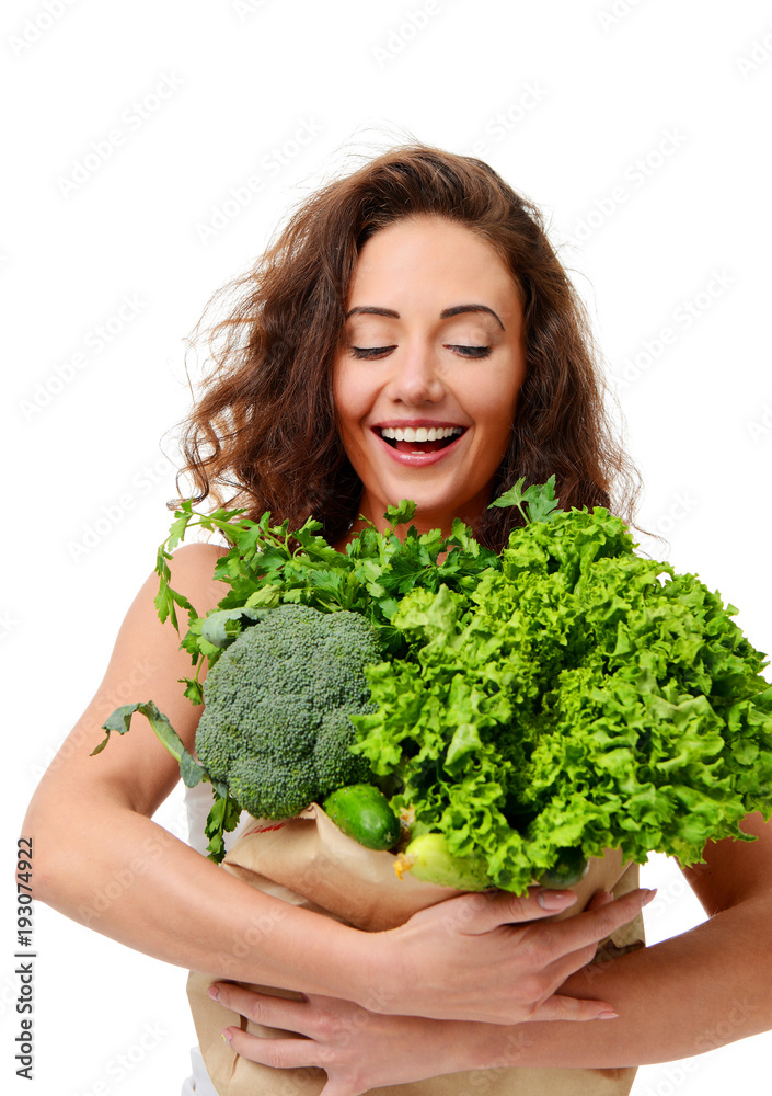 Young woman hold grocery paper shopping bag full of fresh green vegetables Young woman hold grocery paper shopping bag full of fresh green vegetables