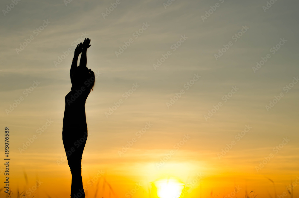 Woman silhouette is standing, raise one's hand for exercise, on evening .