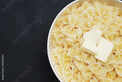 Top view of Farfalle Pasta in Bowl with Butter Close Up over Dark Background with copy space.