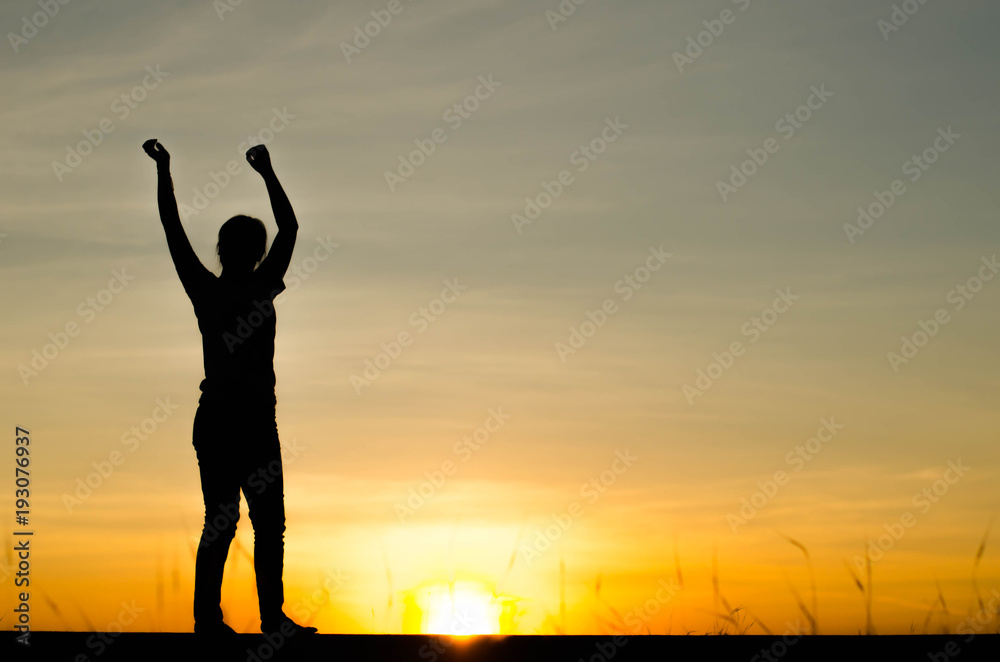 Fototapeta premium Woman silhouette is standing, raise one's hand for exercise, on evening .