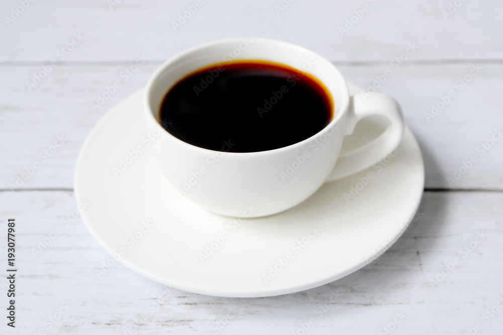 Top view of black coffee inside white cup on white wooden background.