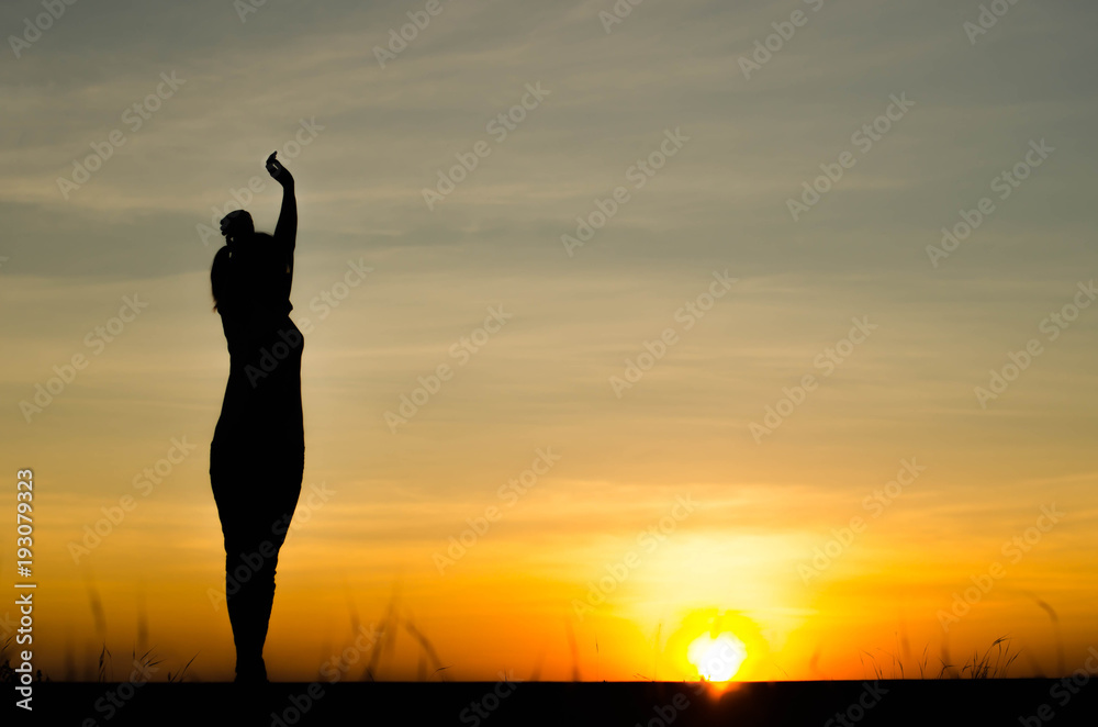 Fototapeta premium Woman silhouette is standing, raise one's hand for exercise, on evening .