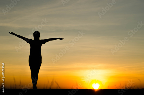 Woman silhouette is standing  raise one s hand for exercise  on evening .
