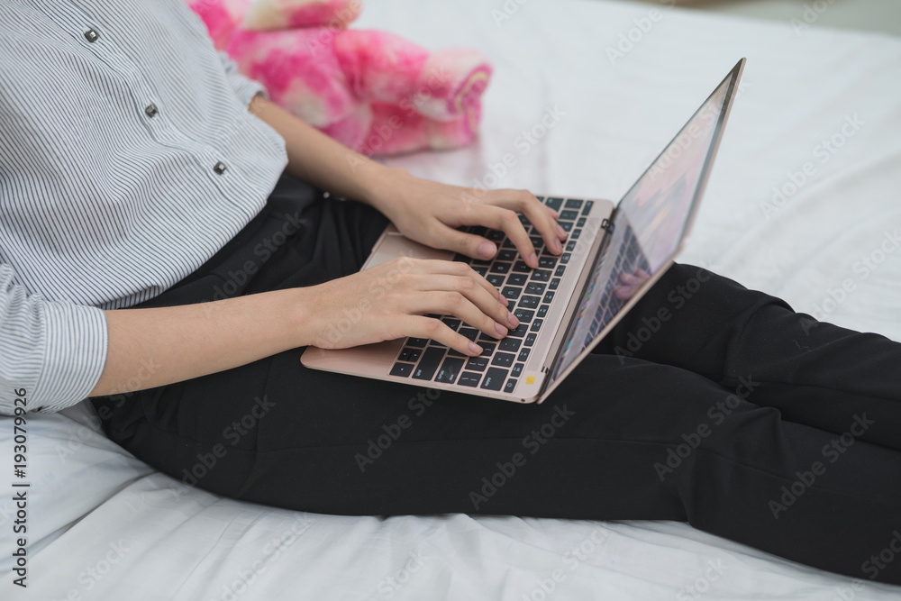 Fototapeta premium Hands of Asian business girl while working with a laptop on bed at home.