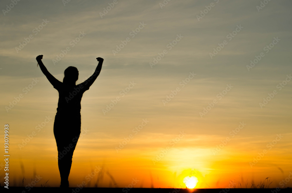 Woman silhouette is standing, raise one's hand for exercise, on evening .