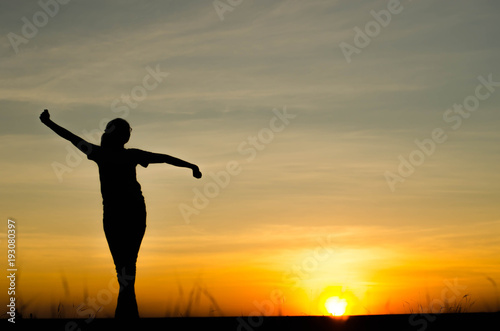 Woman silhouette is standing, raise one's hand for exercise, on evening .
