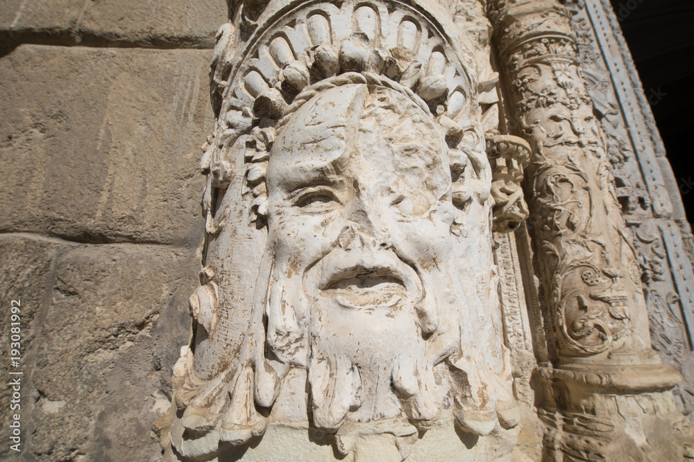 broken face sculpture and art relief on exterior facade of ancient building of Museum Santa Cruz, landmark and monument of the Sixteenth century in Toledo city, Spain, Europe
