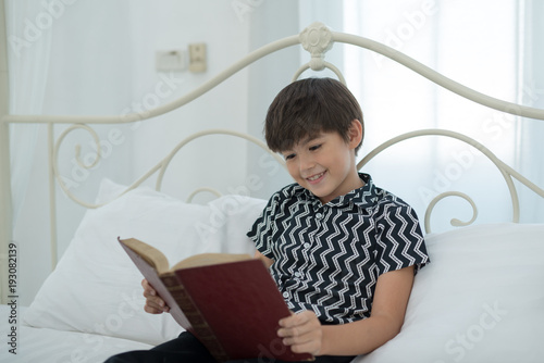 Boy reading a book, smiling, happy in bed. education concept