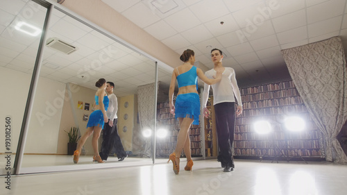 Young attractive man and woman dancing and practicing Latin dance in costumes in the Studio