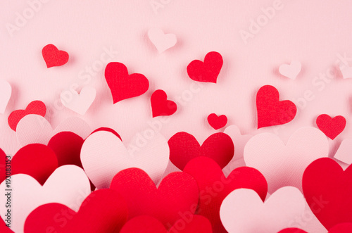 Valentine day background. Stream of fly out red and pink paper hearts on pink color backdrop..