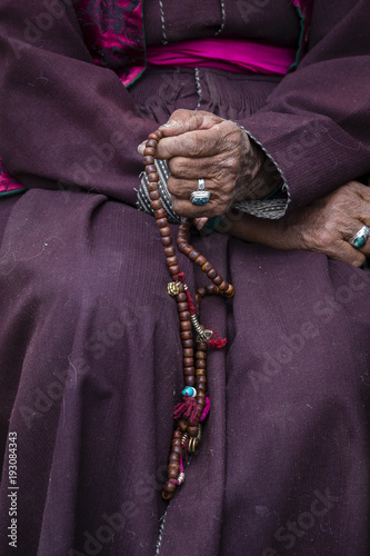 Old Tibetan woman holding buddhist rosary in Hemis monastery, Ladakh, India. Hand and rosary, close up