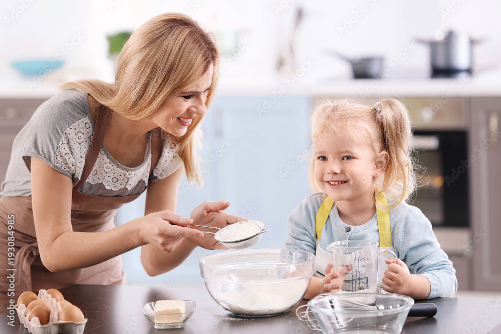 Mother and daughter preparing dough indoors Mother and daughter preparing dough indoors