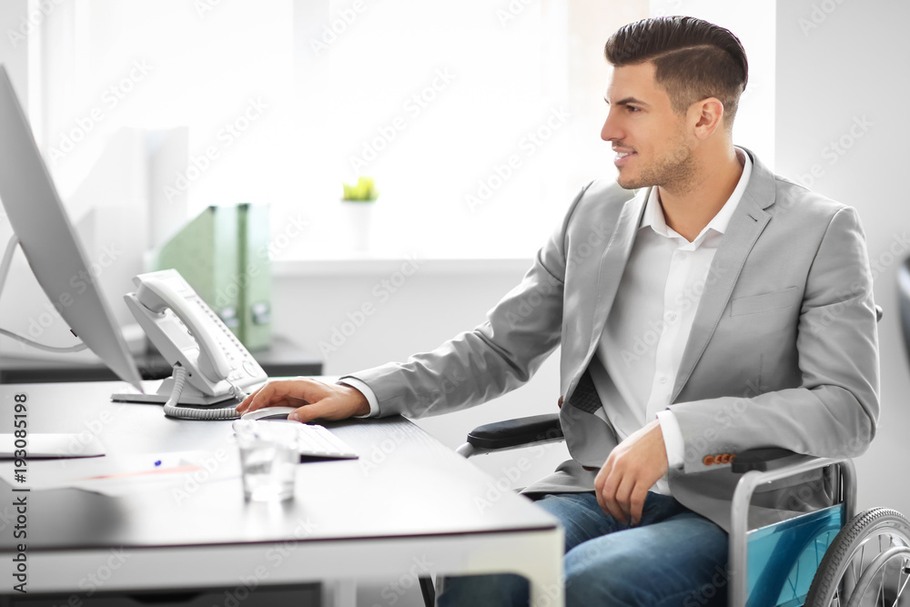 Young man in wheelchair at workplace Young man in wheelchair at workplace