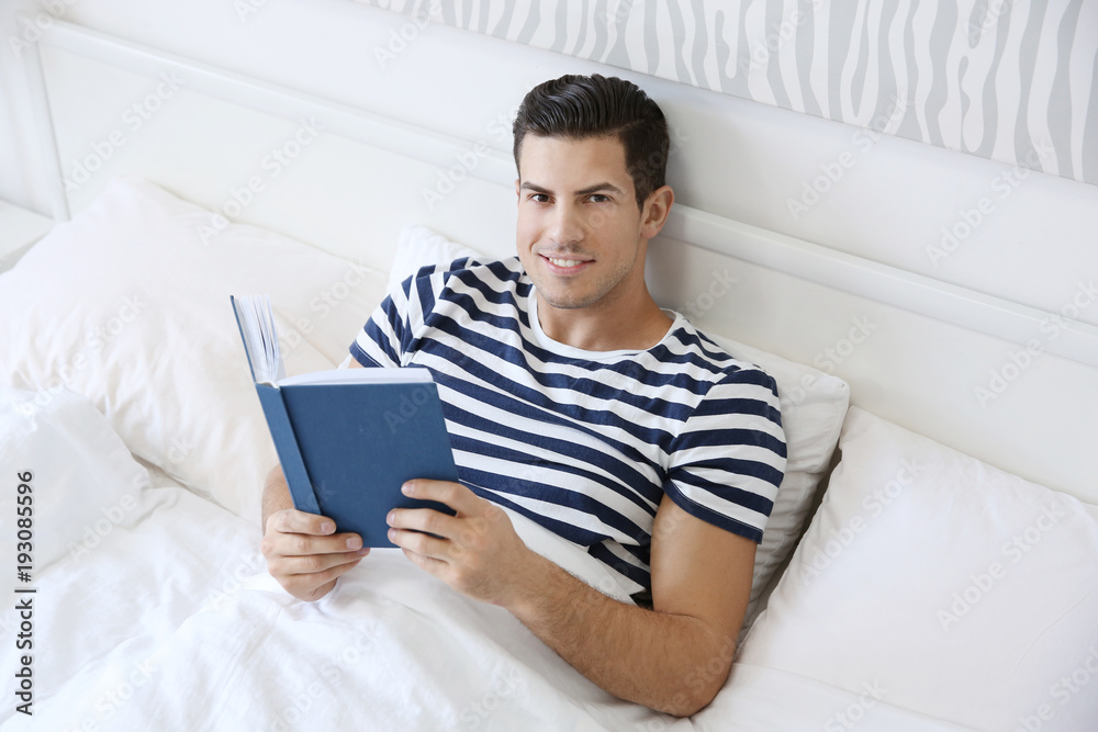 Young handsome man reading book in bed at home Young handsome man reading book in bed at home