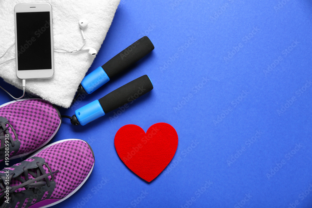 Gym stuff, phone and red heart on color background. Cardio training concept Gym stuff, phone and red heart on color background. Cardio training concept