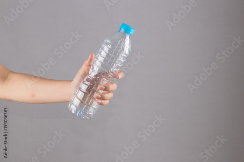female hand holding a plastic bottle without water.