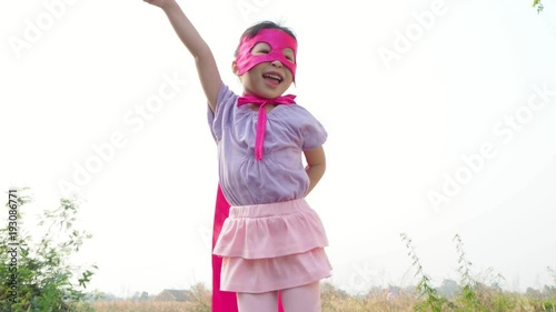 Little asian girl in pink superhero costume playing outdoor 