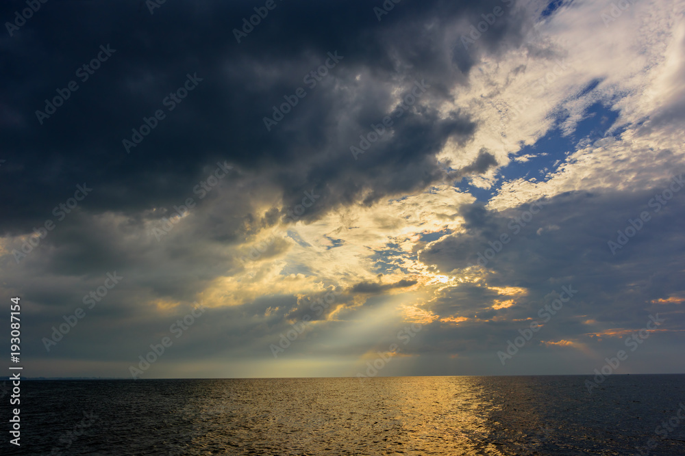 The rays of the sun, making their way through thunderclouds over the ocean