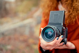 Close up of female hands holding vintage retro camera outdoors.
