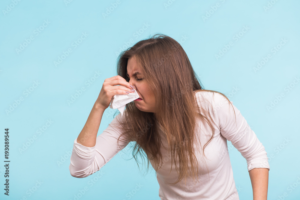 Young woman with handkerchief. Sick girl isolated has runny nose on blue background Young woman with handkerchief. Sick girl isolated has runny nose on blue background