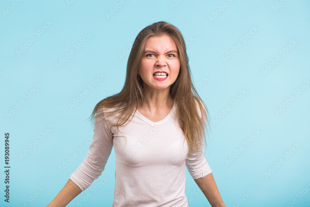Angry aggressive woman with ferocious expression on blue background Angry aggressive woman with ferocious expression on blue background