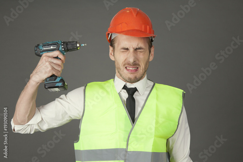 Builder in a helmet tries to shoot himself with a screwdriver photo