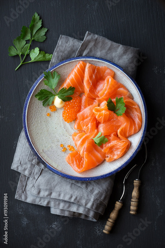 Smoked salmon slices with salted salmon caviar decorated with fresh parsley leaves