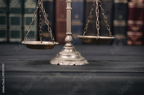  Scales of Justice on a black wooden background.