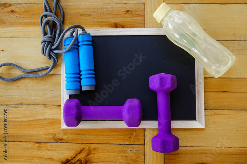Sports, fitness concept. Running sneakers, water bottle, headphones, dumbbells, smartphone, on wooden background top view copy space