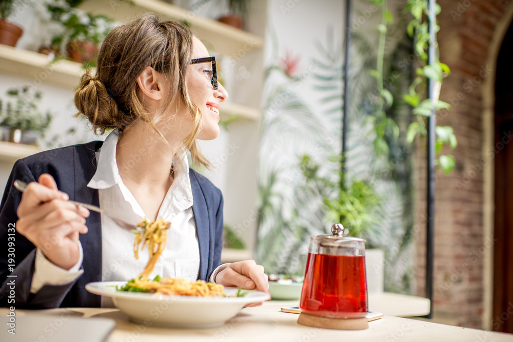 Businesswoman having lunch with pasta and fruit tea at the vegan restaurant on the green background
