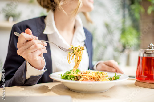 Businesswoman having lunch with pasta and fruit tea at the vegan restaurant on the green background photo