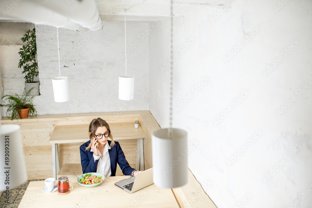 Businesswoman during the lunch sitting in the white cafe interior. Wide view with copy space Businesswoman during the lunch sitting in the white cafe interior. Wide view with copy space