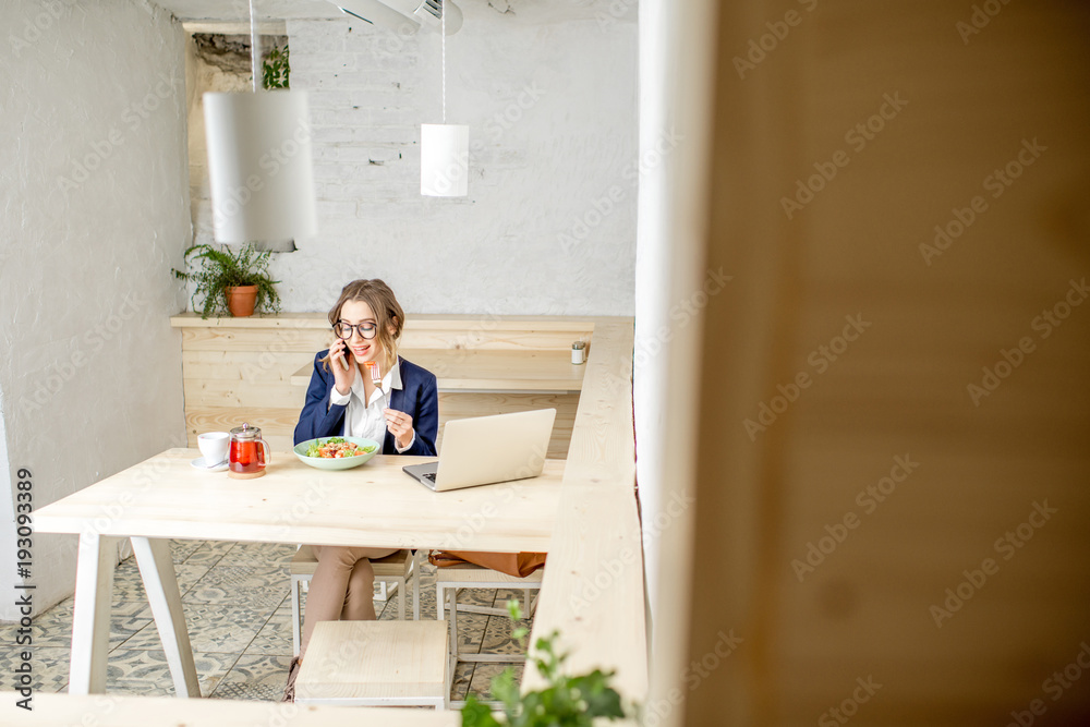 Businesswoman during the lunch sitting in the white cafe interior. Wide view with copy space Businesswoman during the lunch sitting in the white cafe interior. Wide view with copy space