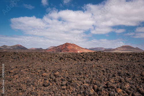 Red volcanic landscape, lava scenary with volcano crater in the background