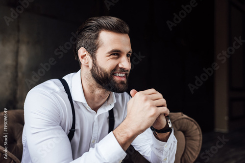 handsome stylish smiling man sitting in armchair