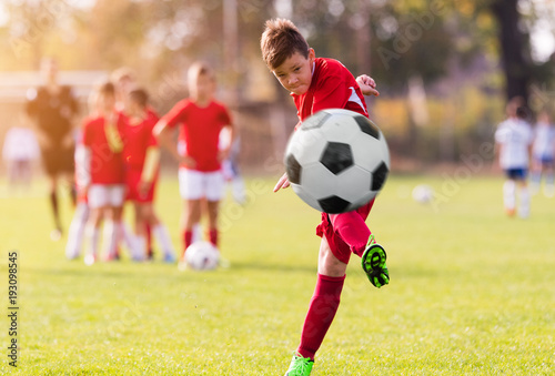 Fototapeta Naklejka Na Ścianę i Meble -  Boy kicking football on the sports field