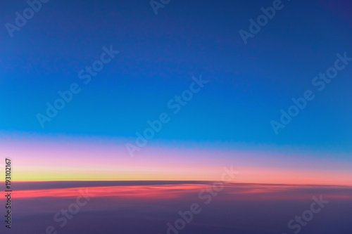 Landscape sunrise above clouds. Wallpaper bright red-orange dawn in dark blue morning sky. View from porthole flying airplane.