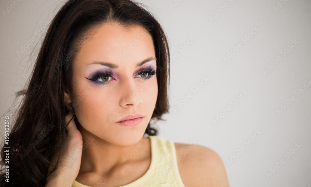 Portrait of attractive young brunette woman posing against light studio background close up Portrait of attractive young brunette woman posing against light studio background close up