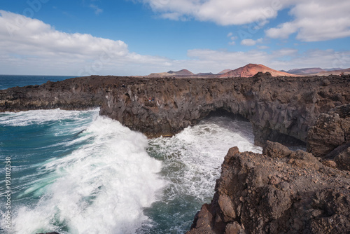 Lanzarote landscape. Los Hervideros coastline  lava caves  cliffs and wavy ocean. Unidentifiable tourist are in the background