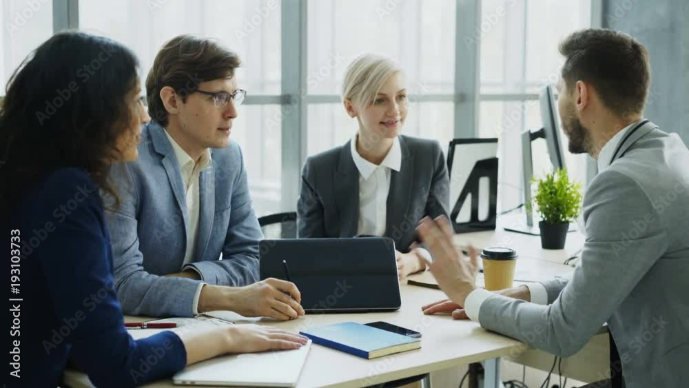 Businessman discussing future business project with male and female colleagues sitting at the table in modern office Businessman discussing future business project with male and female colleagues sitting at the table in modern office