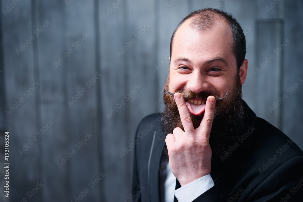 Funny beard and moustache. Young bearded man showing tongue. Funny beard and moustache. Young bearded man showing tongue.