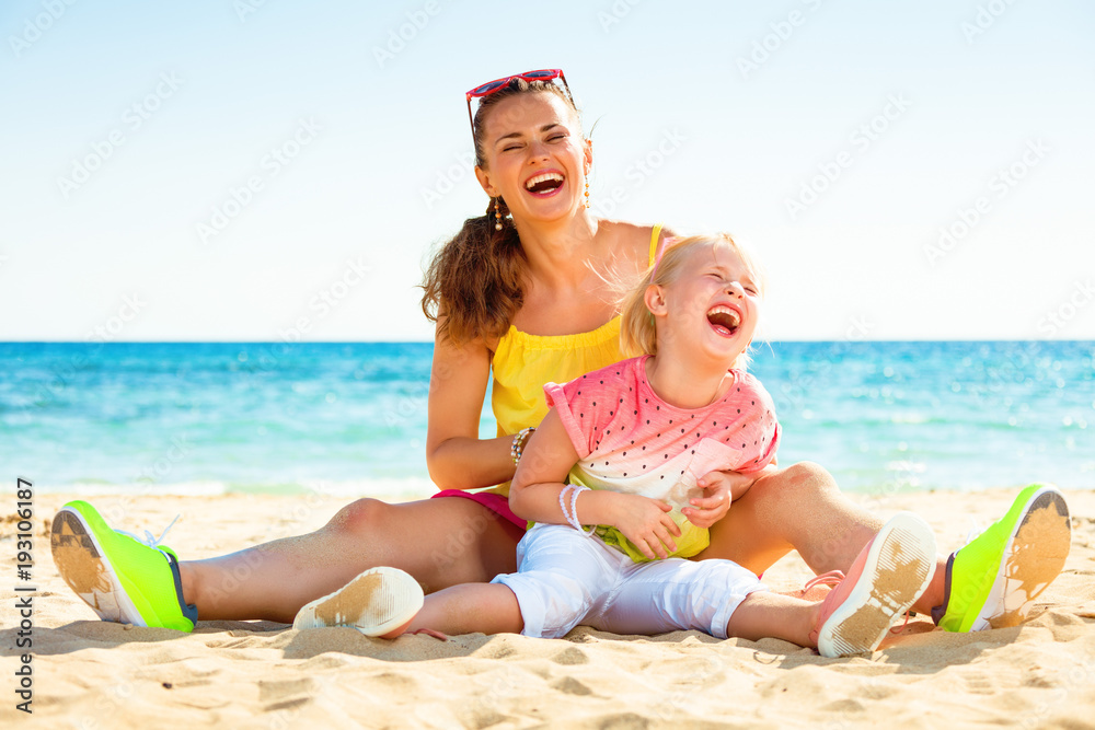 smiling trendy mother and daughter on seashore having fun time smiling trendy mother and daughter on seashore having fun time