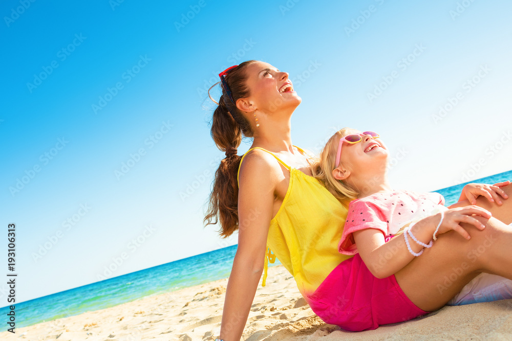 smiling mother and daughter on seashore looking at copy space