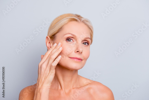 Pretty  charming  attractive woman touching  enjoying her perfect face skin  holding fingers on cheek  pimple  whelk  pustule  dry  oiled  problem skin concept  isolated on grey background