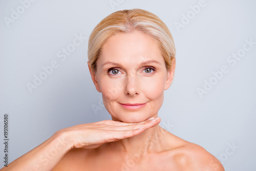 Pretty, attractive, charming, woman demonstrate, show, present her perfect skin after peeling, lotion, mask, isolated on grey background, holding hand under chin, treatment, therapy concept