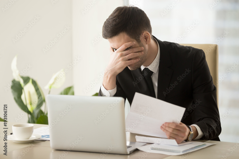Businessman shocked with bad news in letter, upset because of loan refusal, feeling suppressed when receiving notification about company bankruptcy or debts to bank. Depression through work dismissal Businessman shocked with bad news in letter, upset because of loan refusal, feeling suppressed when receiving notification about company bankruptcy or debts to bank. Depression through work dismissal