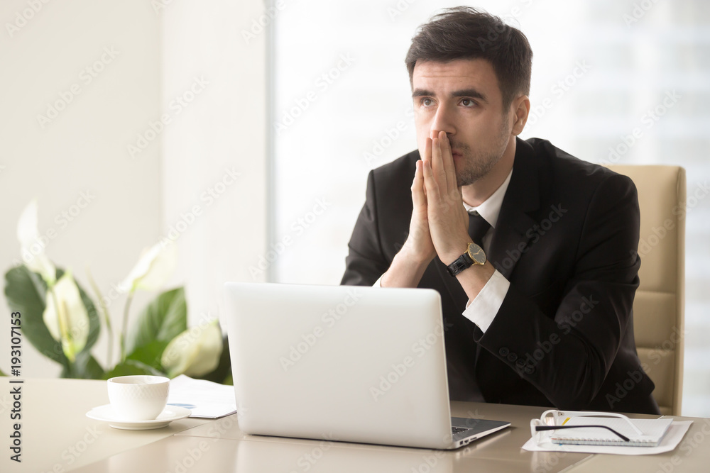 Worried company leader thinking about problem solution, pondering important question, frustrated because of difficulties in business while sitting at desk. Religious businessman praying at workplace Worried company leader thinking about problem solution, pondering important question, frustrated because of difficulties in business while sitting at desk. Religious businessman praying at workplace